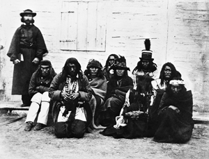 Photo de Jean L’Heureux en soutane et un groupe de Pieds-Noirs, de Gens-du-Sang et de Piégans.